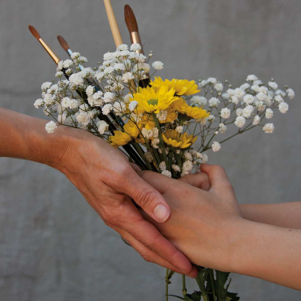Hands holding bouquet of flowers and brushes